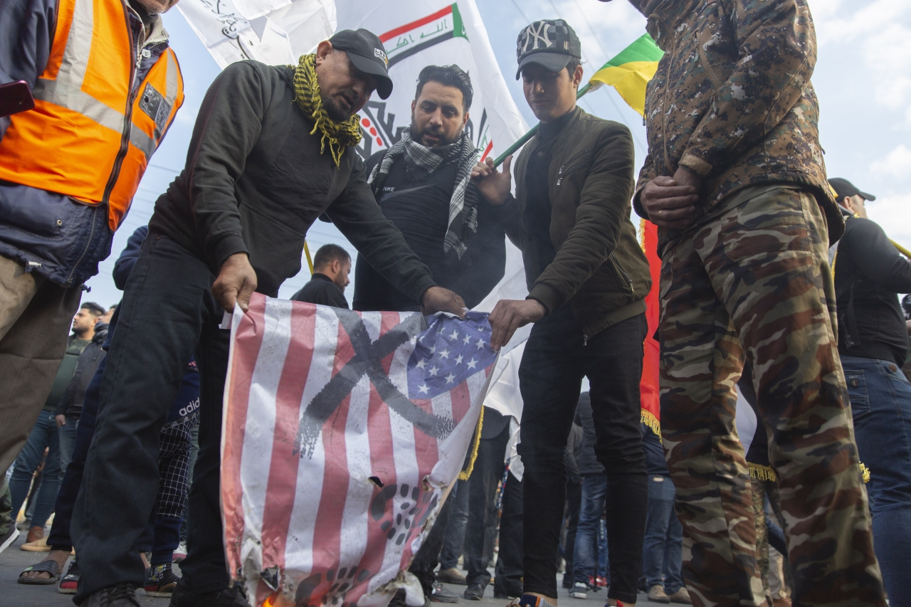4일(현지시간) 이란의 거셈 솔레이마니 혁명수비대 쿠드스군 사령관의 추모 행사가 벌어진 이라크 바그다드에서 몇몇 시민들이 미국의 성조기를 불태우고 있다. ⓒAP