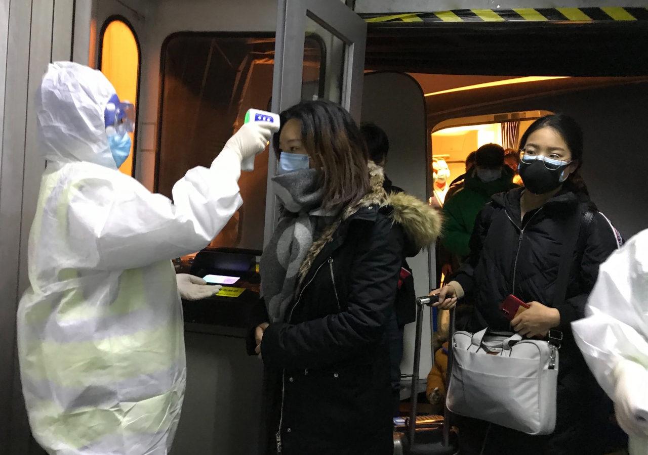 보호복을 입은 보건 관계자들이 22일 중국 베이징 공항에서 우한시에서 도착한 승객들의 체온을 체크하고 있다. 중국은 신종 코로나바이러스로 발생하는 우한 폐렴의 확산을 막기 위해 23일부터 모든 항공기와 열차들의 우한 출발을 막기 시작했다. ⓒap
