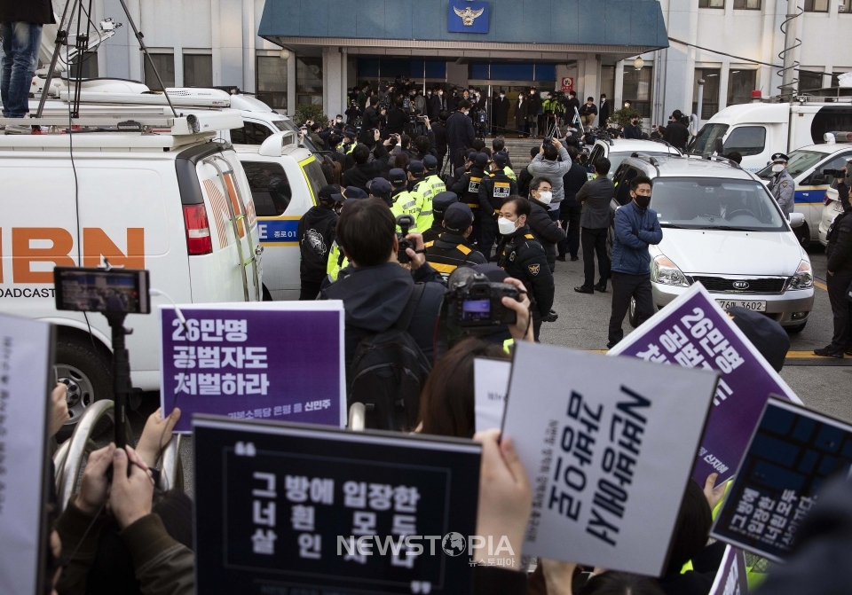 25일 오전 미성년자를 포함한 여성들을 협박, 성 착취물을 제작·유포한 텔레그램 'n번방' 박사방의 운영자 조주빈이 검찰에 송치되기 전 종로경찰서에서 기자들의 질문에 답을 하고 있는 가운데 시민단체 회원들이 종로경찰서 밖에서 조주빈의 강력처벌을 요구하는 시위를 벌이고 있다.