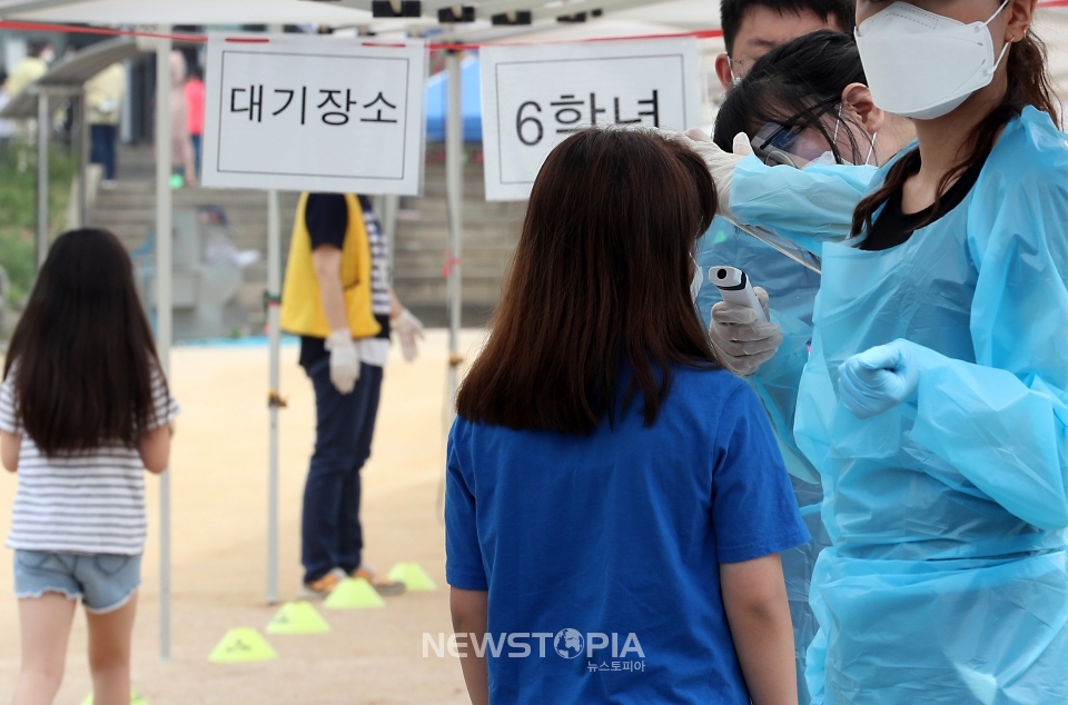 인천지역에 신종 코로나바이러스 감염증(코로나19) 확진자가 속출한 17일 오전 확진자가 나온 인천시 미추홀구 한 초등학교에서 학생들이 줄지어 운동장에 마련된 선별진료소로 들어가고 있다.