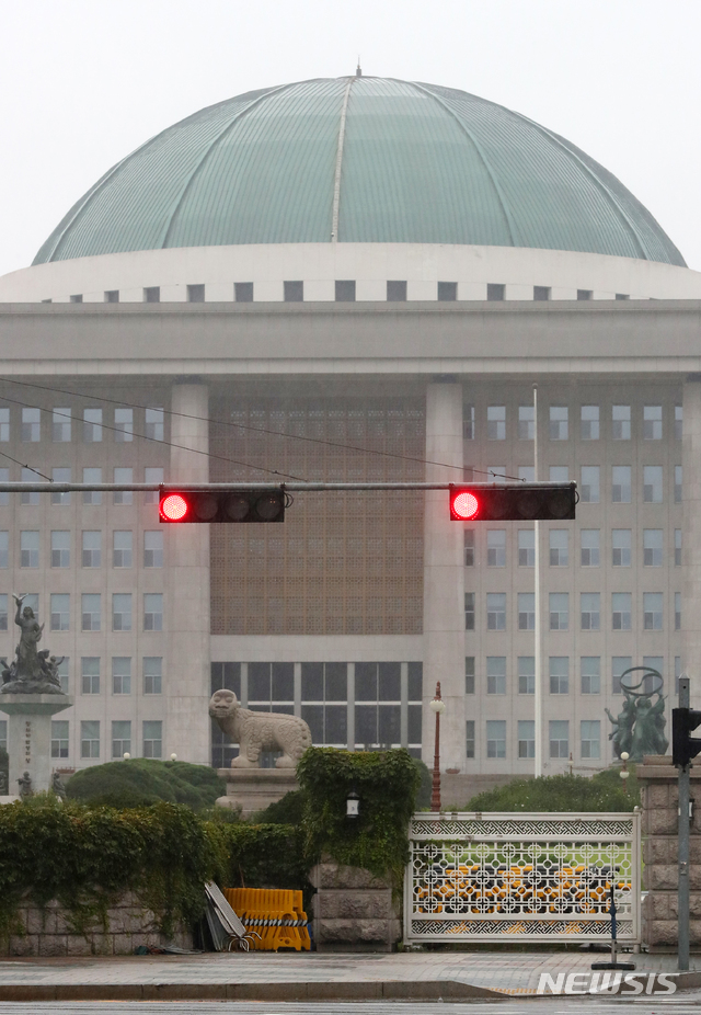 출입기자의 신종 코로나바이러스 감염증(코로나19) 확진으로 국회가 폐쇄된 27일 오전 서울 여의도 국회의사당 앞 도로에 빨간불이 켜져 있다.