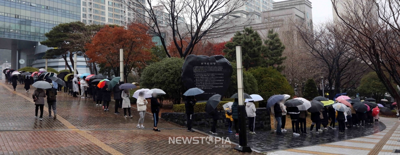 연일 코로나19 확진자가 폭증하고 있는 상황 속에서 16일 부산 남구 보건소 선별진료소를 찾은 시민들이 진단검사를 받기 위해 우산을 쓴 채 길게 줄을 서고 있다. ⓒ뉴시스