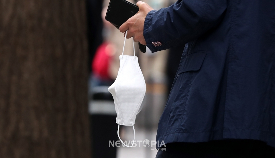 정부의 새 거리두기 조정안에 야외 마스크 착용 의무화 일부 해제 방안이 논의되고 있는 14일 오후 서울 도심에서 시민이 마스크를 손에 들고 있다.ⓒ뉴시스