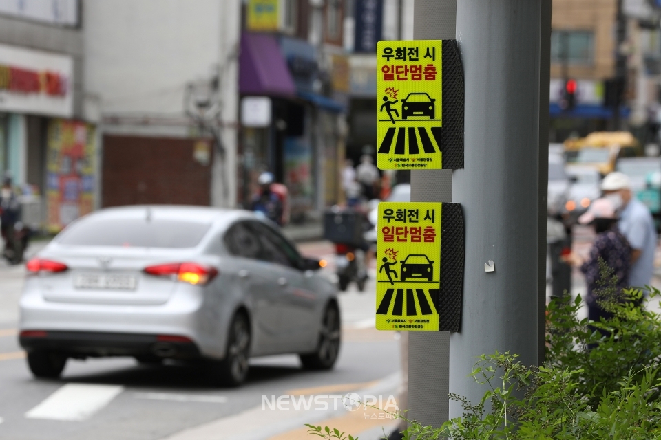 횡단보도 앞 일시정지 의무를 확대하는 등 보행자 보호의무가 강화된 도로교통법 시행 첫날인 12일 오후 서울 시내 한 횡단보도 옆에 '우회전 시 일단멈춤' 안내문이 부착돼 있다.ⓒ뉴시스