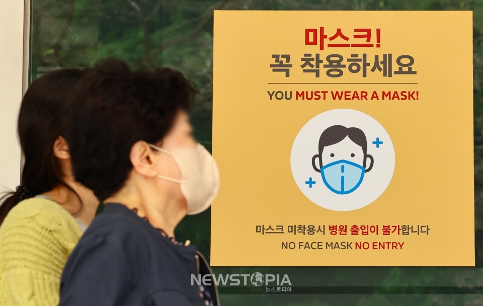 서울 시내 한 대형병원에 게시된 마스크 착용 안내문 앞으로 내원객들이 이동하고 있다. ⓒ뉴시스