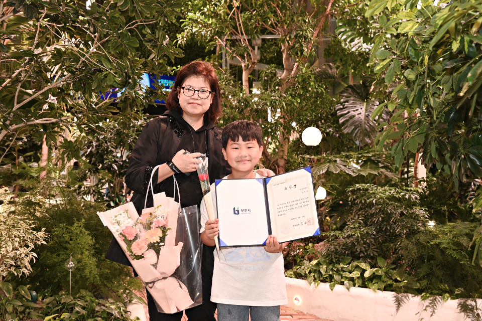 정태운 군과 그의 어머니가 부천시로부터 모범 어린이 표창장을 받은 뒤 환하게 웃고 있다. (사진=부천시 제공)